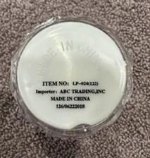 Underside label on recalled WSDZ light-up shot glass showing item number LP-024 122 and importer ABC Trading Inc